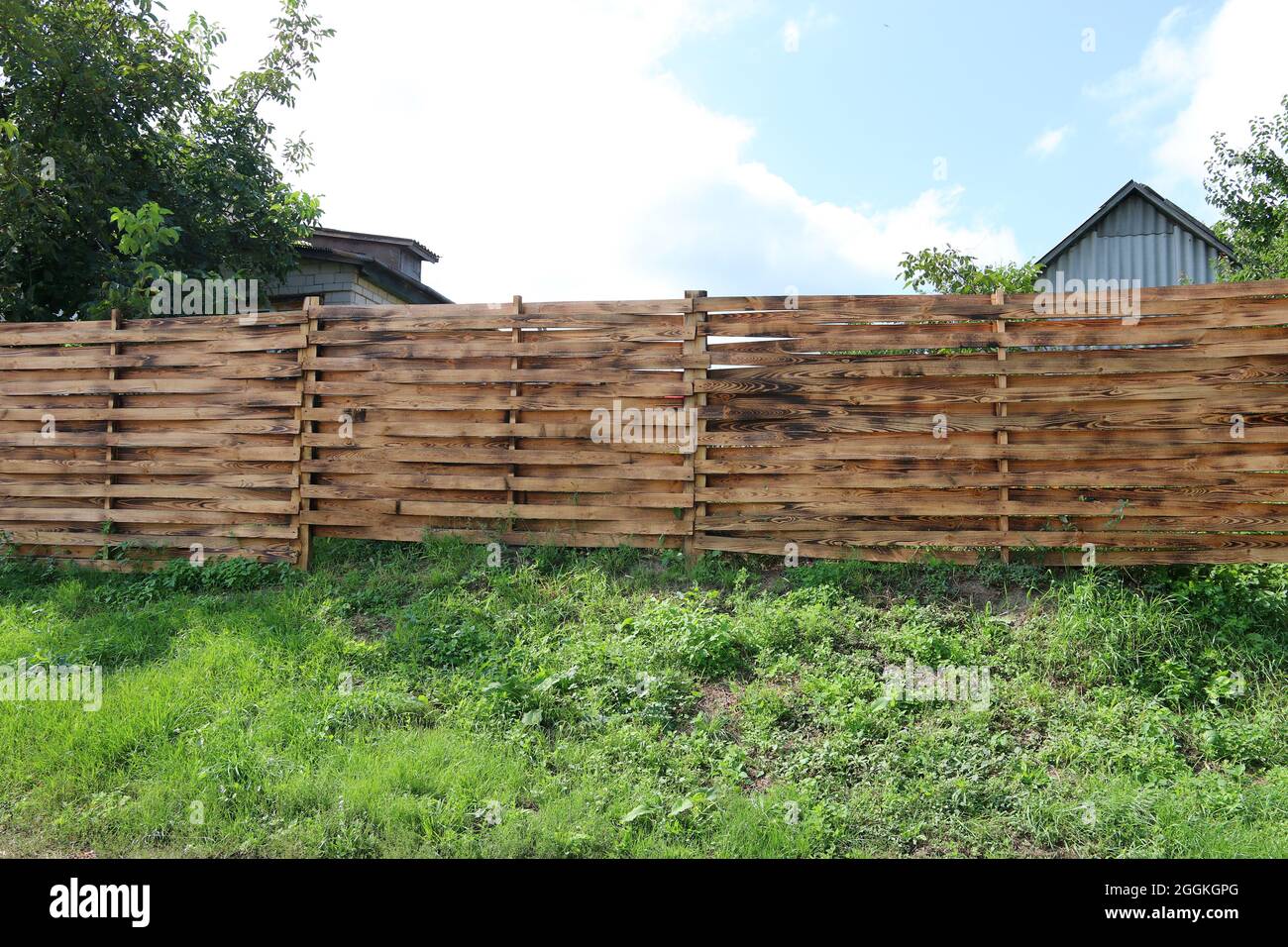 Beautiful wooden fence against a background of green grass and blue sky ...