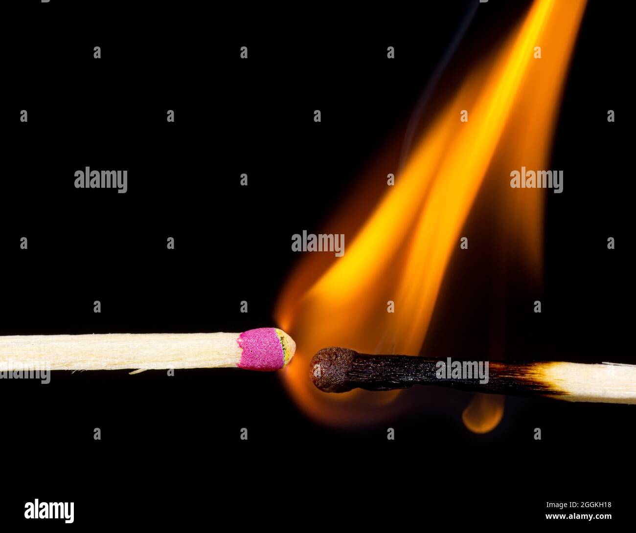 Closeup of a burning match igniting the other one against a black