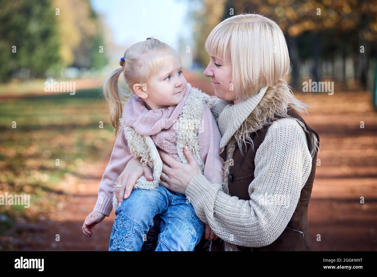 Scene of quiet family happiness filiation and love. Happy caucasian mother holding her little daughter on her laps face to face closely looking into Stock Photo