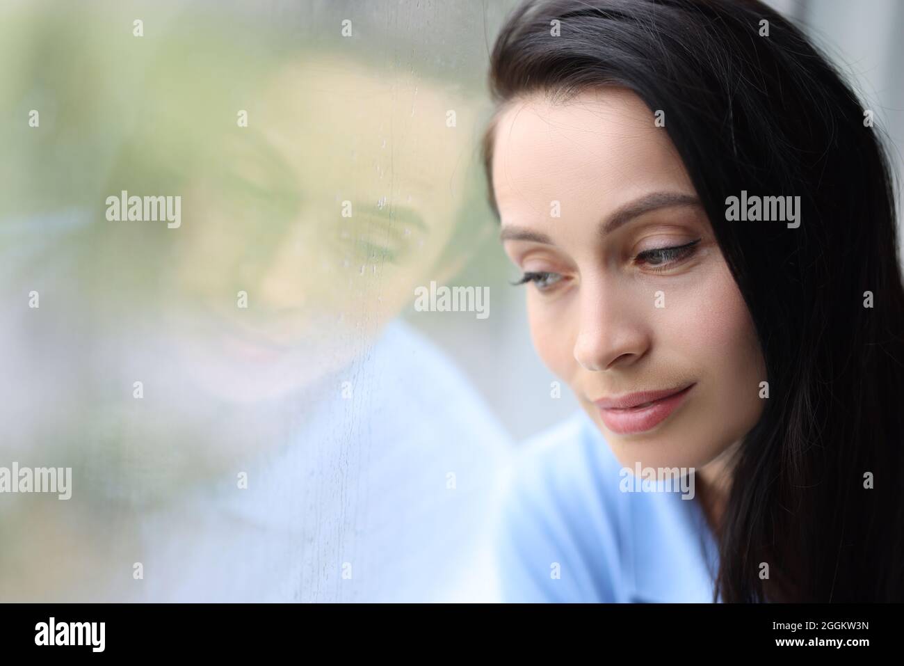 Pensive pensive girl sits alone and looks out window closeup Stock Photo