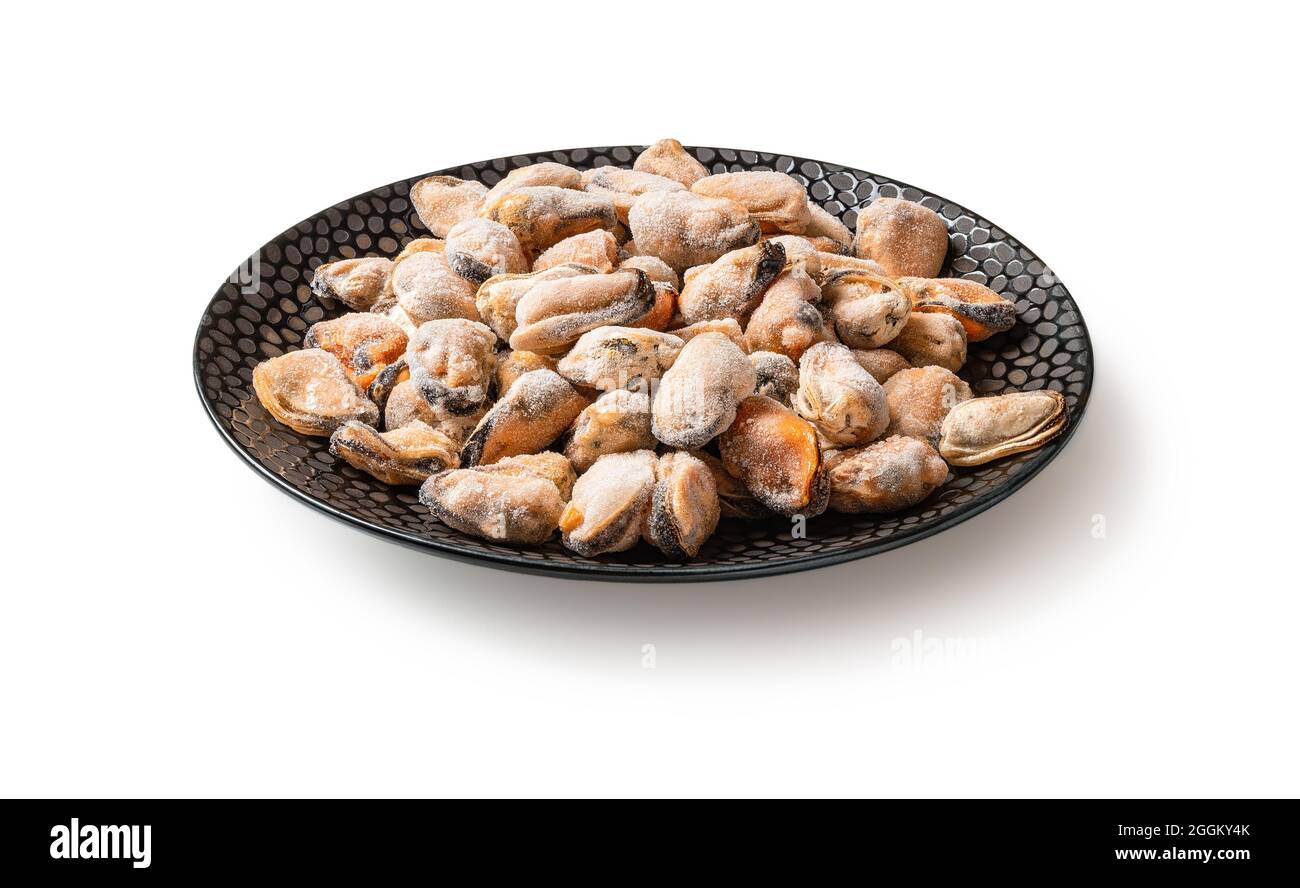 Frozen peeled mussels on a black plate isolated on a white background. Cooking shellfish. Mussel