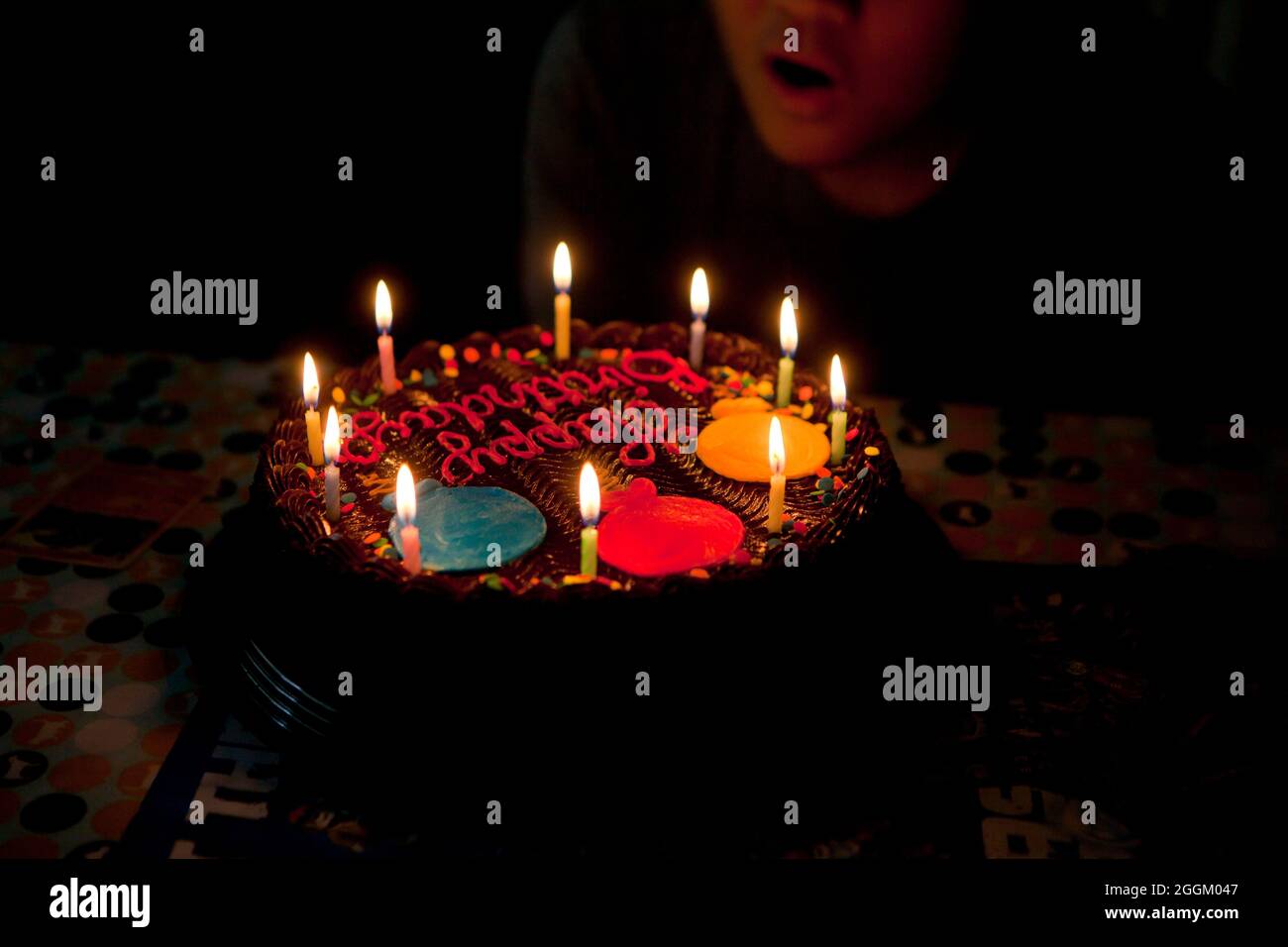 Boy blowing out candles on chocolate birthday cake - USA Stock Photo