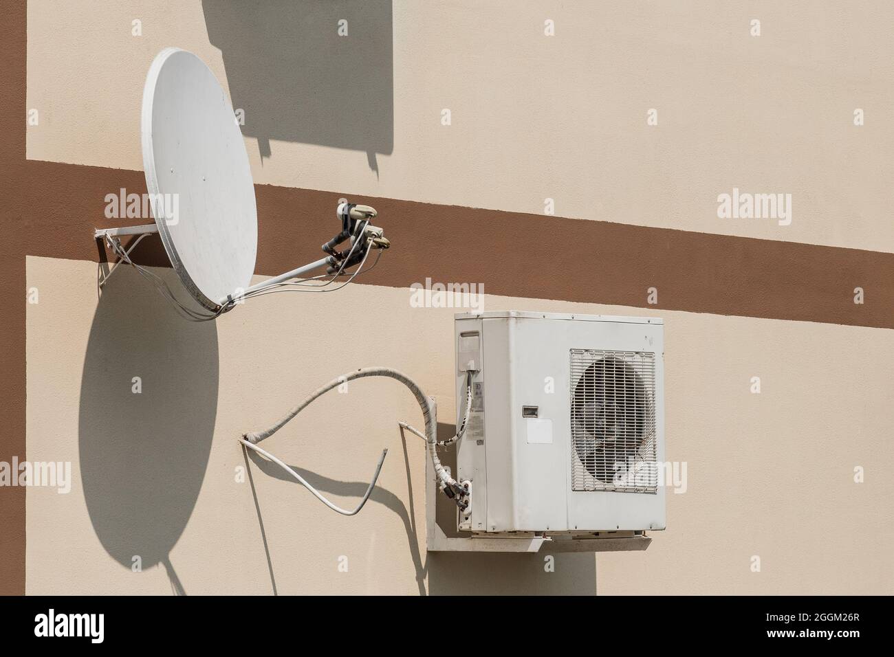 Air conditioner and satellite dish on the wall of a modern home on the street outdoor. Stock Photo