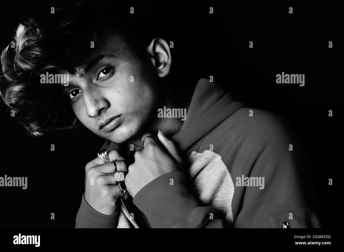 Grayscale shot of a young Indian man wearing a hoodie Stock Photo