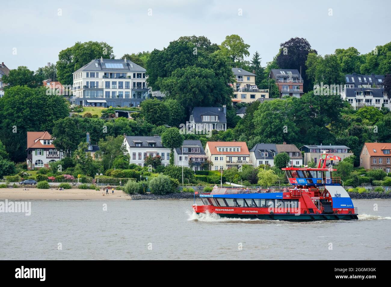 Hamburg, Germany - Residential houses on the sandy Elbe beach in the affluent residential area in Othmarschen, in front a harbor ferry, the Reeperbahn liner boat. Stock Photo