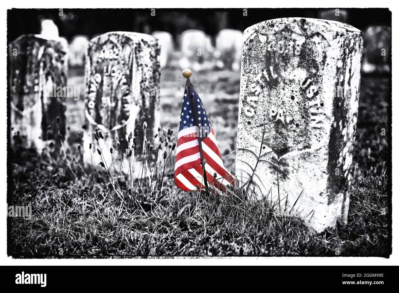 Color with greyscale photo of small American flag marking the graves of union fatalities at the Antietam National Cemetery in Sharpesburg, Maryland. Stock Photo