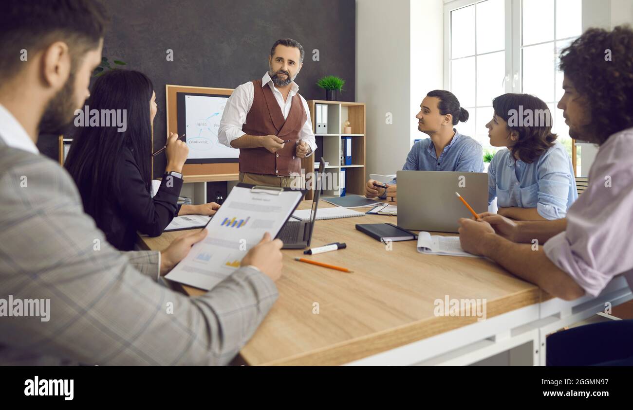 Group of people listening to a senior man while having a business meeting at work Stock Photo
