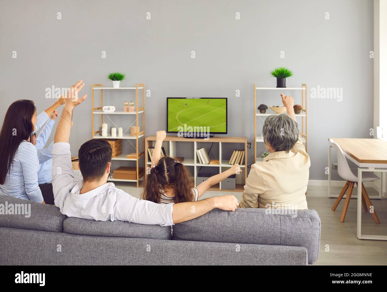 Super excited and happy big family team watch football match together on the couch at home. Stock Photo