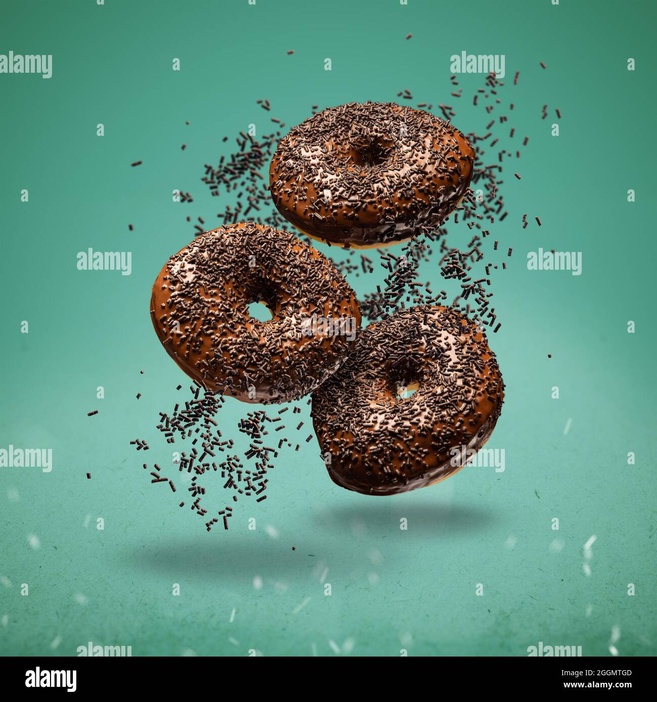 Sweet chocolate doughnuts in motion falling on green background. Stock Photo