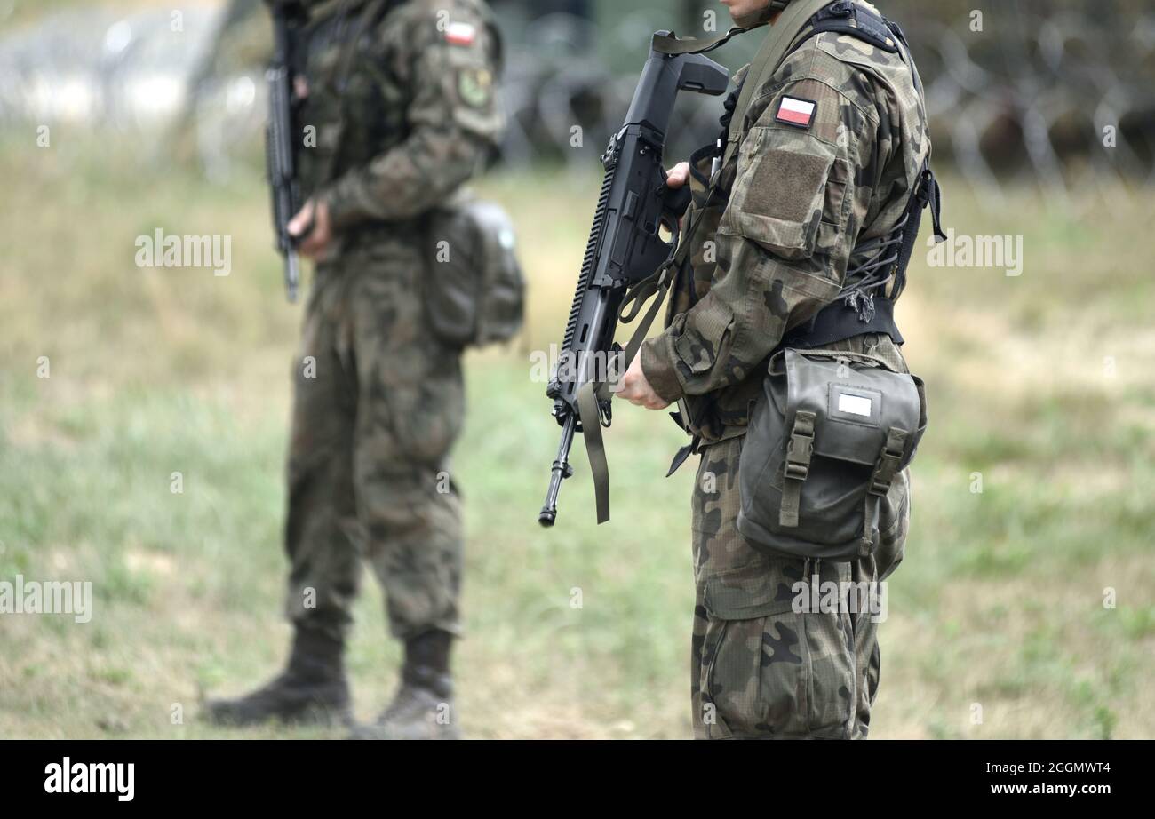 Soldiers of Poland with assault rifle and flag of Poland on military uniform. Polish soldiers with assault rifle. Stock Photo
