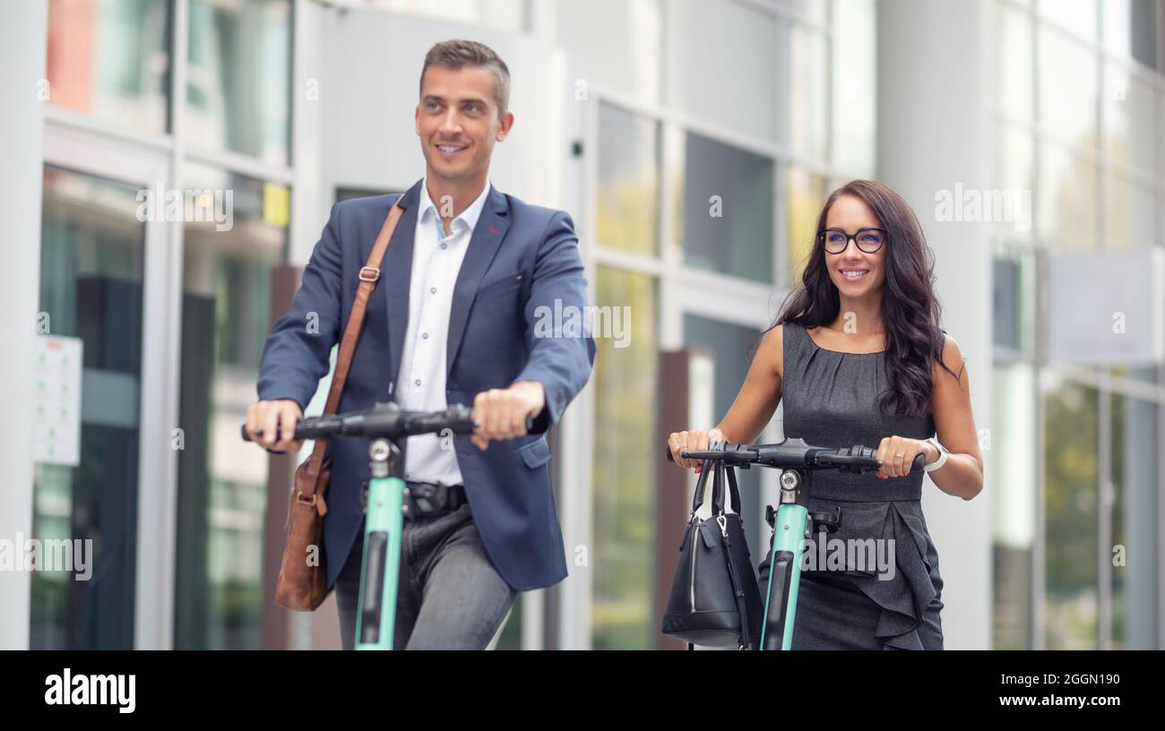Office employees commute to work in a modern way, using e-mobility electric scooters. Stock Photo