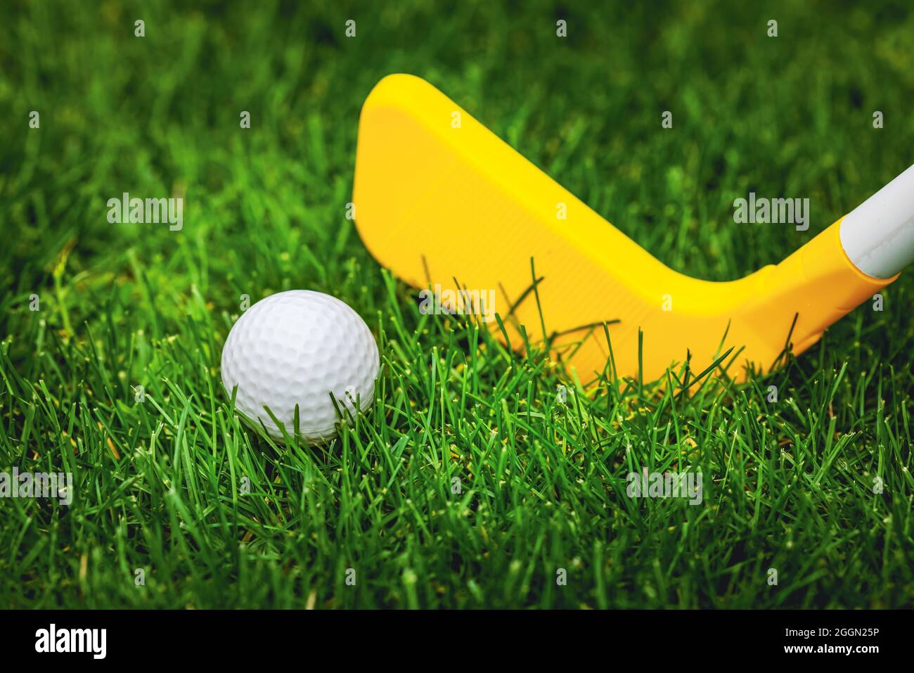 plastic toy golf ball and club on green grass Stock Photo