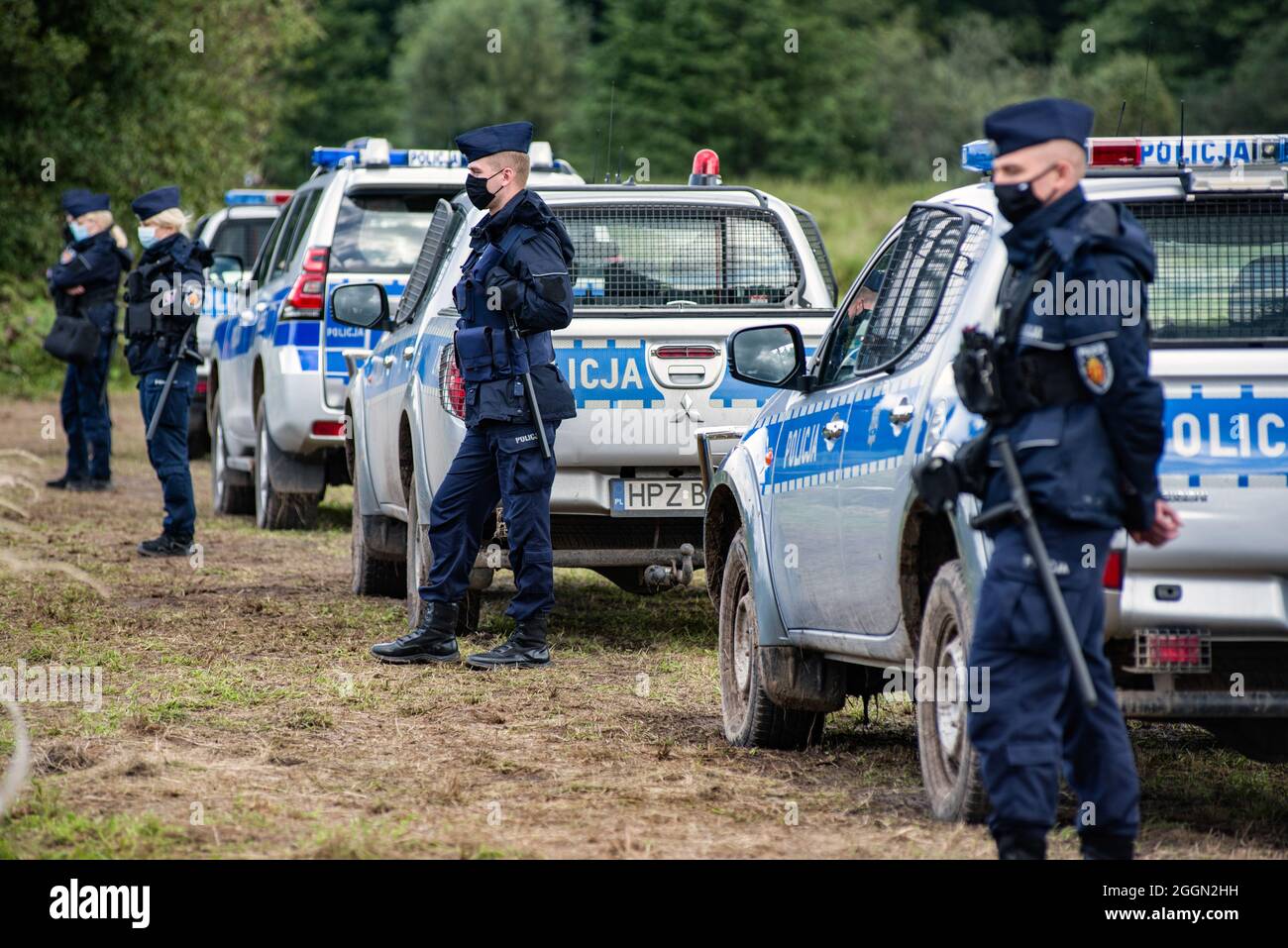 Police officers next to the village of Usnarz Gorny are standing on guard on the field next to a makeshift camp where a group of migrants stay and not being let into the Polish side. The Polish government is introduce a State of Emergency on the border with Belarus in two voivodeships (the highest-level administrative division of Poland) to stop migrants crossing illegally. Under a state of emergency, Polish authorities will have the power to restrict the movement of people, including aid organisations or press in border areas. It's the first such measure since the 1981 declaration of martial Stock Photo