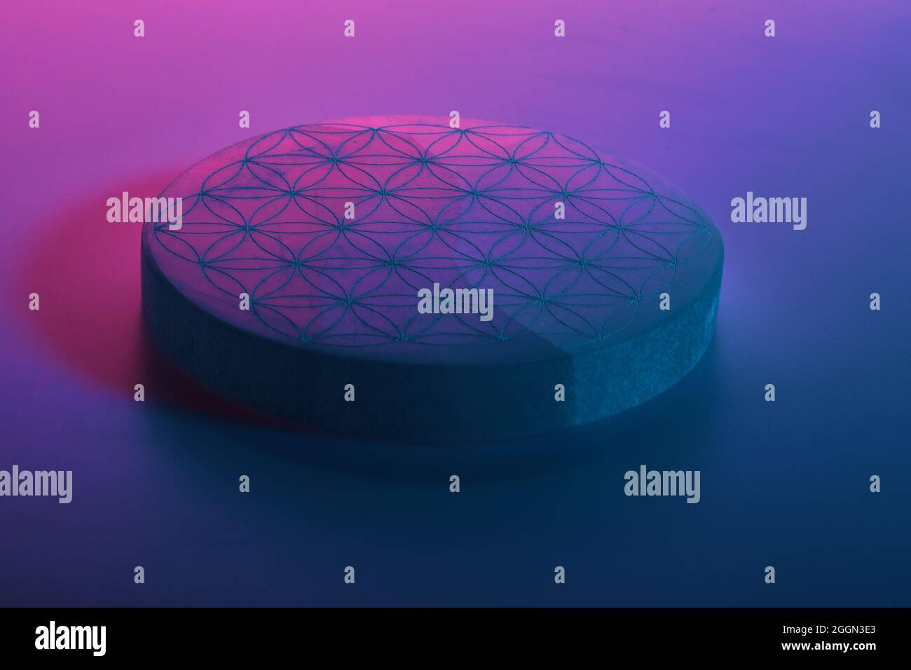 Round stone with carving under blue purple and red neon lights Stock Photo