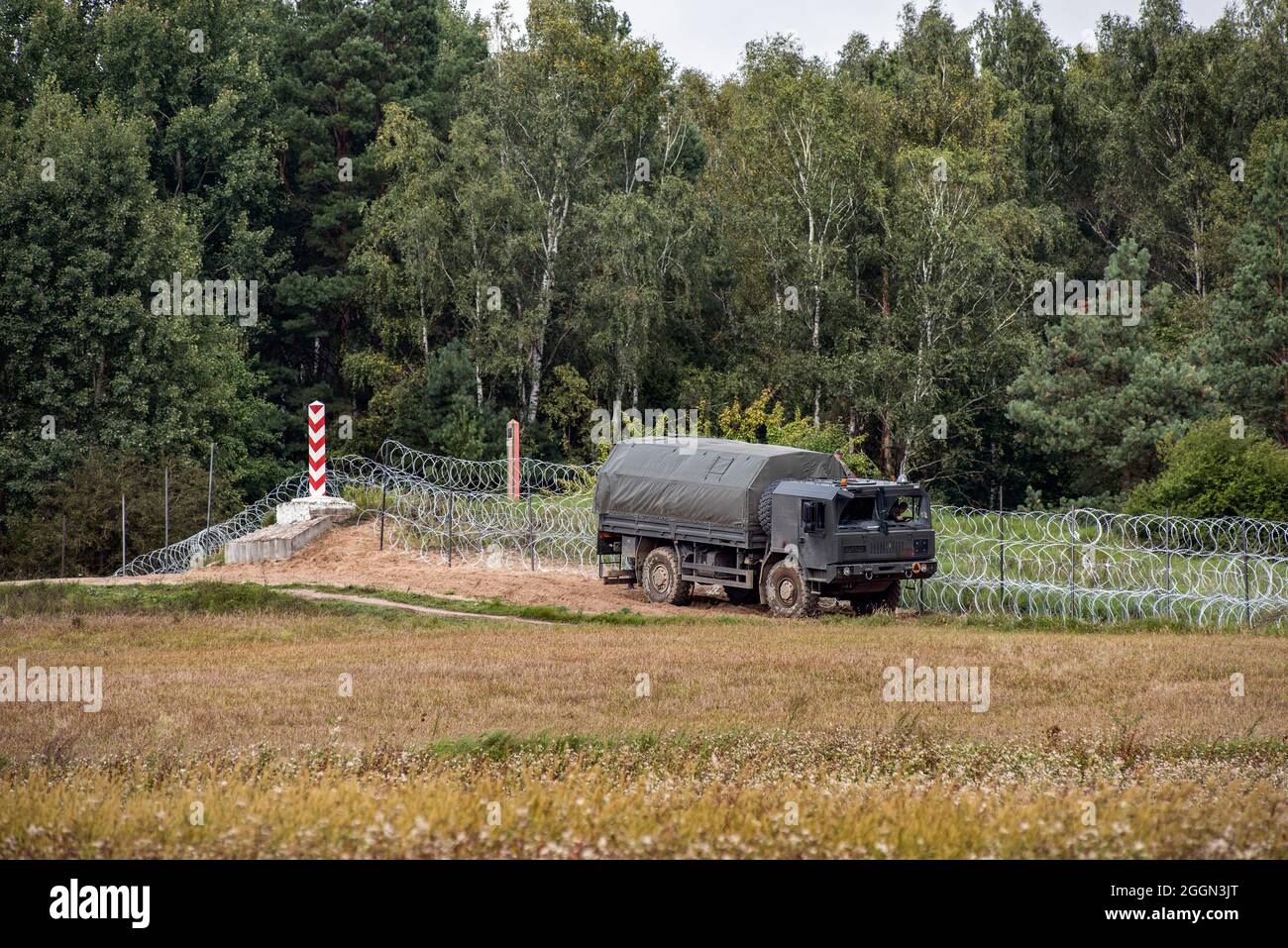 An army truck drives along the border razor wire fence near the village of Minkowce.The Polish government is introduce a State of Emergency on the border with Belarus in two voivodeships (the highest-level administrative division of Poland) to stop migrants crossing illegally. Under a state of emergency, Polish authorities will have the power to restrict the movement of people, including aid organisations or press in border areas. It's the first such measure since the 1981 declaration of martial law during communist times; past governments avoided declaring a state of emergency for natural dis Stock Photo