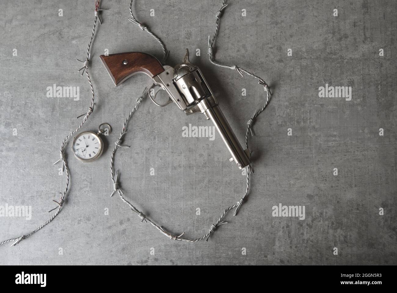 cowboy pistol, colt, with barbed wire and a pocket watch still life Stock Photo