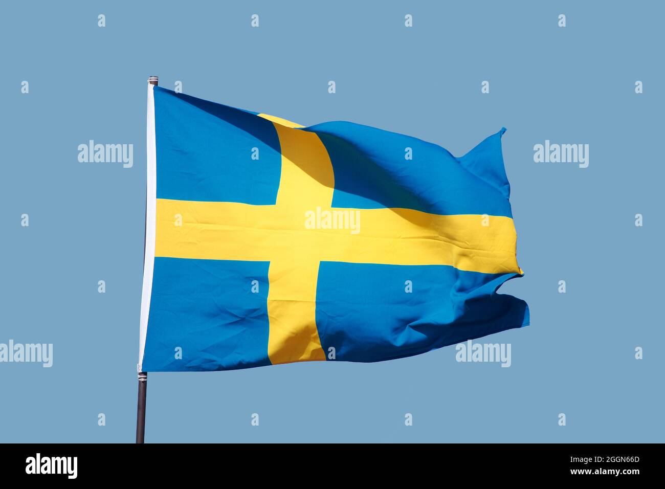 Swedish flag flying on flagpole on blue sky background Stock Photo