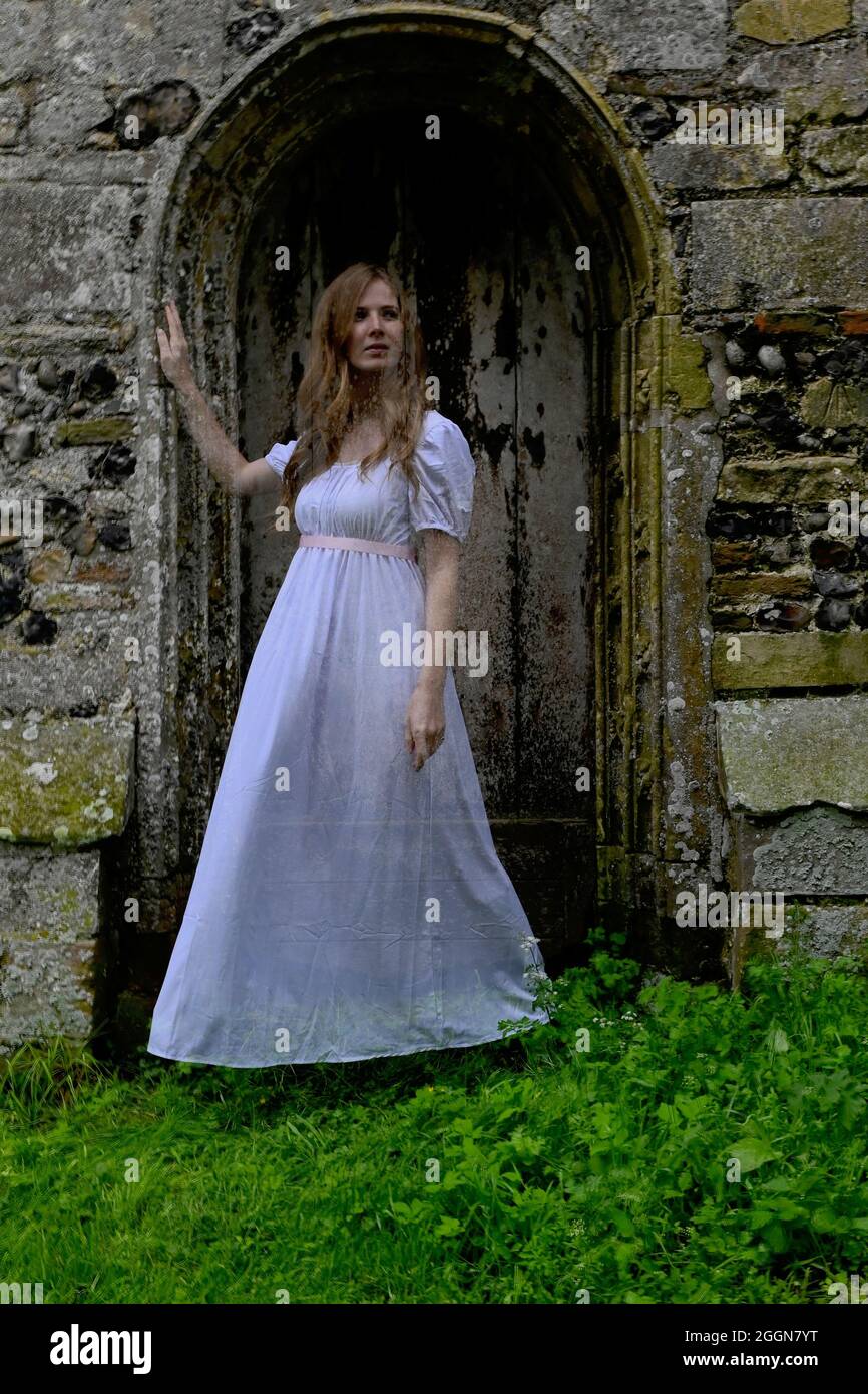ghostly translucent woman in white haunting old church doorway Stock Photo