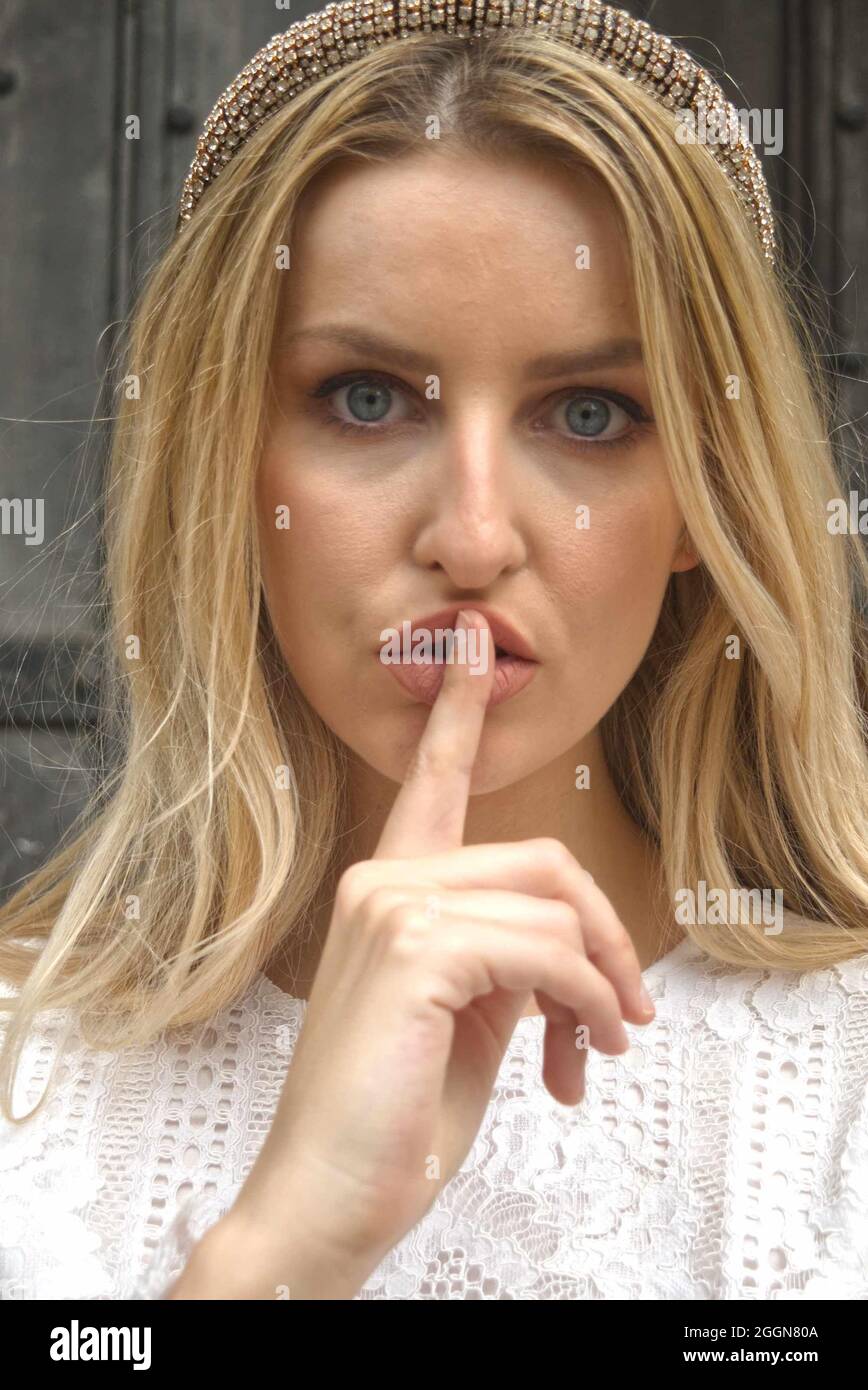 Hush. Beautiful blonde woman with her finger to her lips. Stock Photo