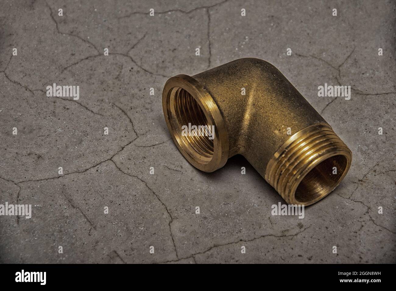 Brass metal fitting on dark gray cement background, close-up, copy space. Connection of plumbing pipes. Renovation concept Stock Photo