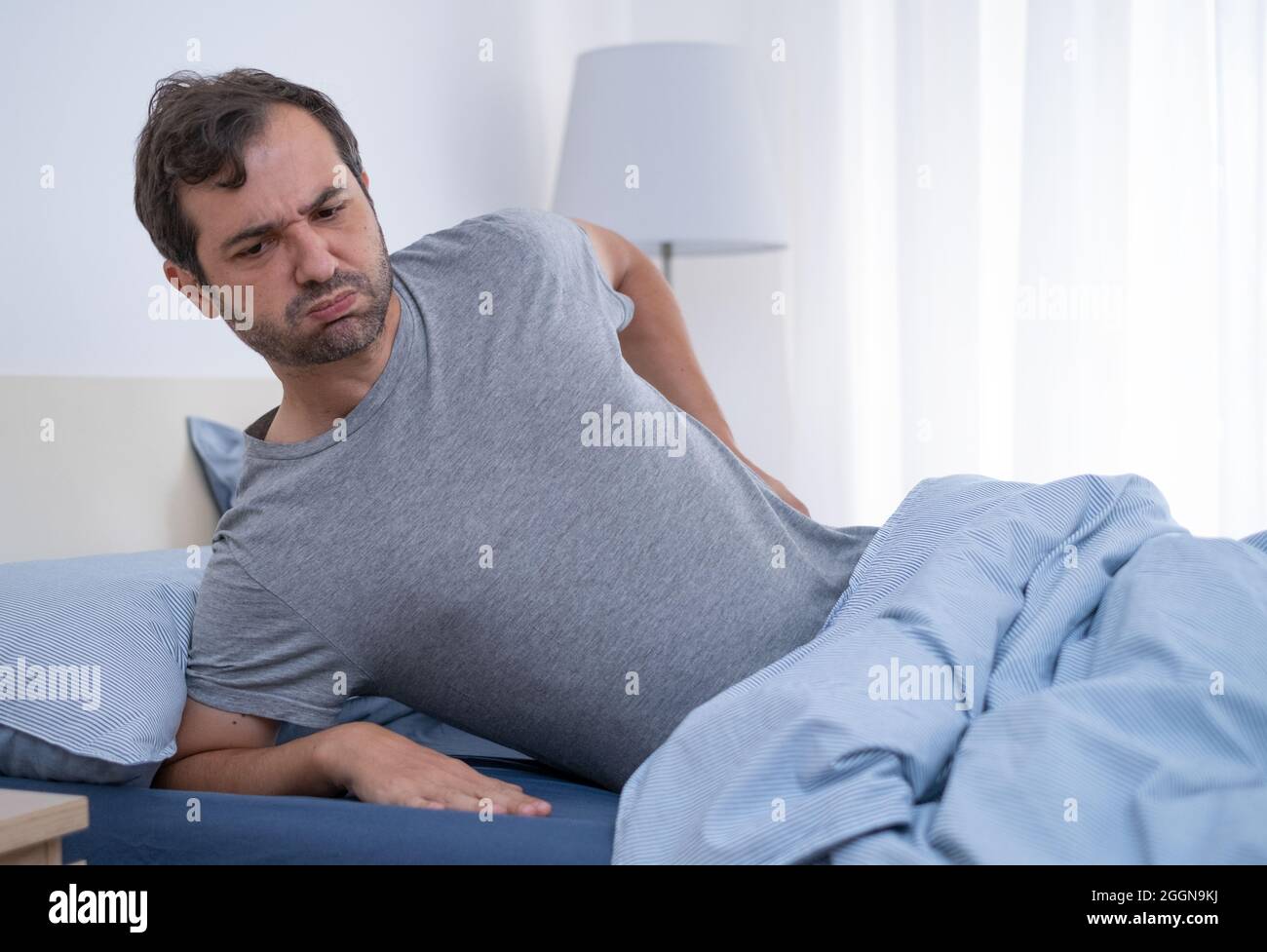 Man lying in bed and suffering from back pain Stock Photo Alamy