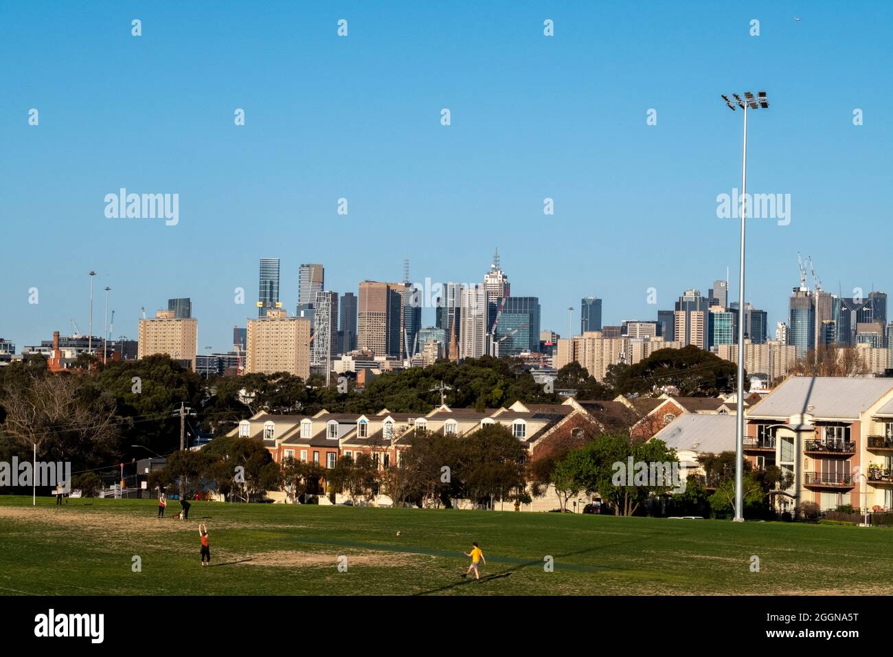 People exercising at the ramsden street oval in front of the city skyline. Melbourne Victoria, Australia Stock Photo