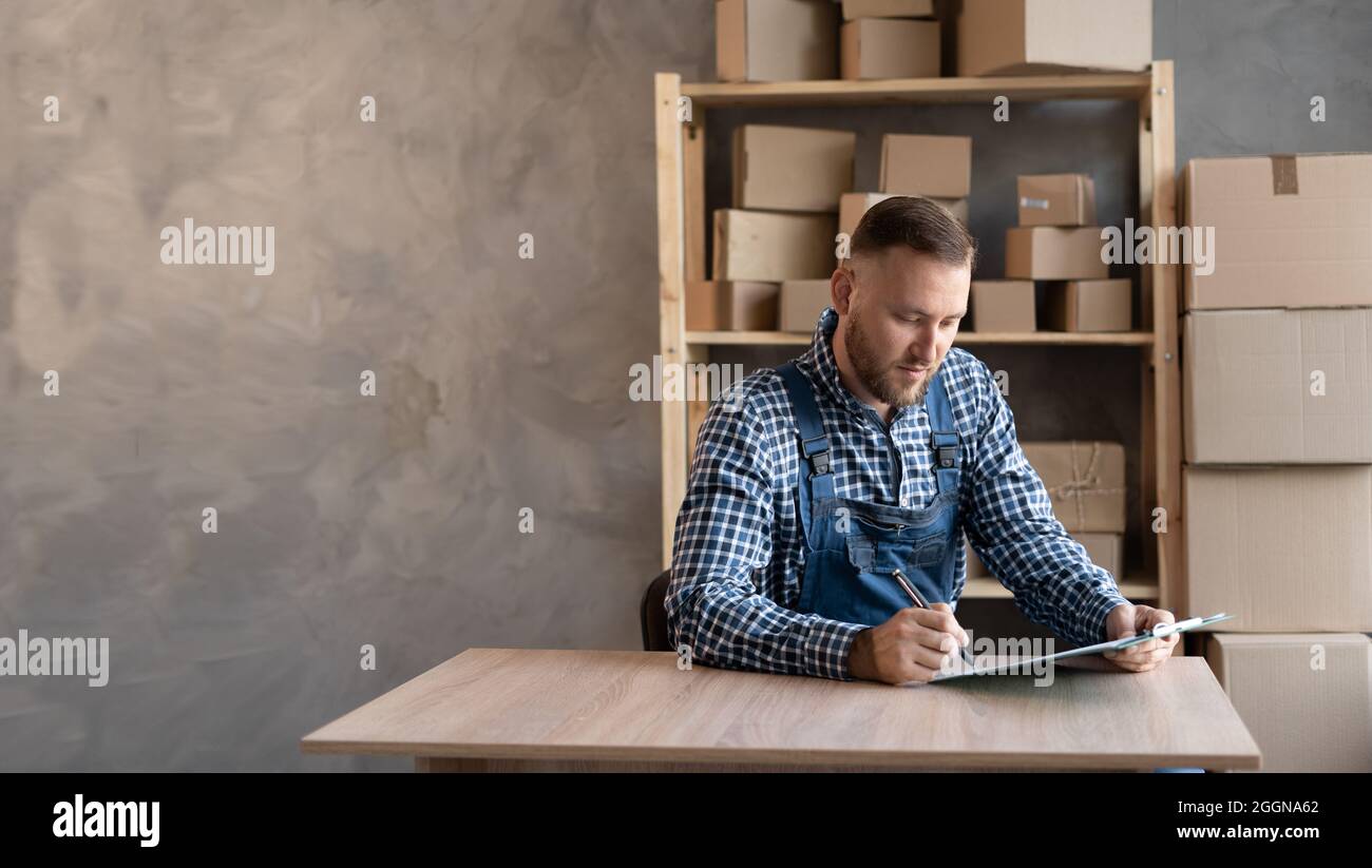 Online Sales Shipment, Small Business Owner Delivery Service. Business owner working Caucasian man wearing overalls checking order for confirmation be Stock Photo
