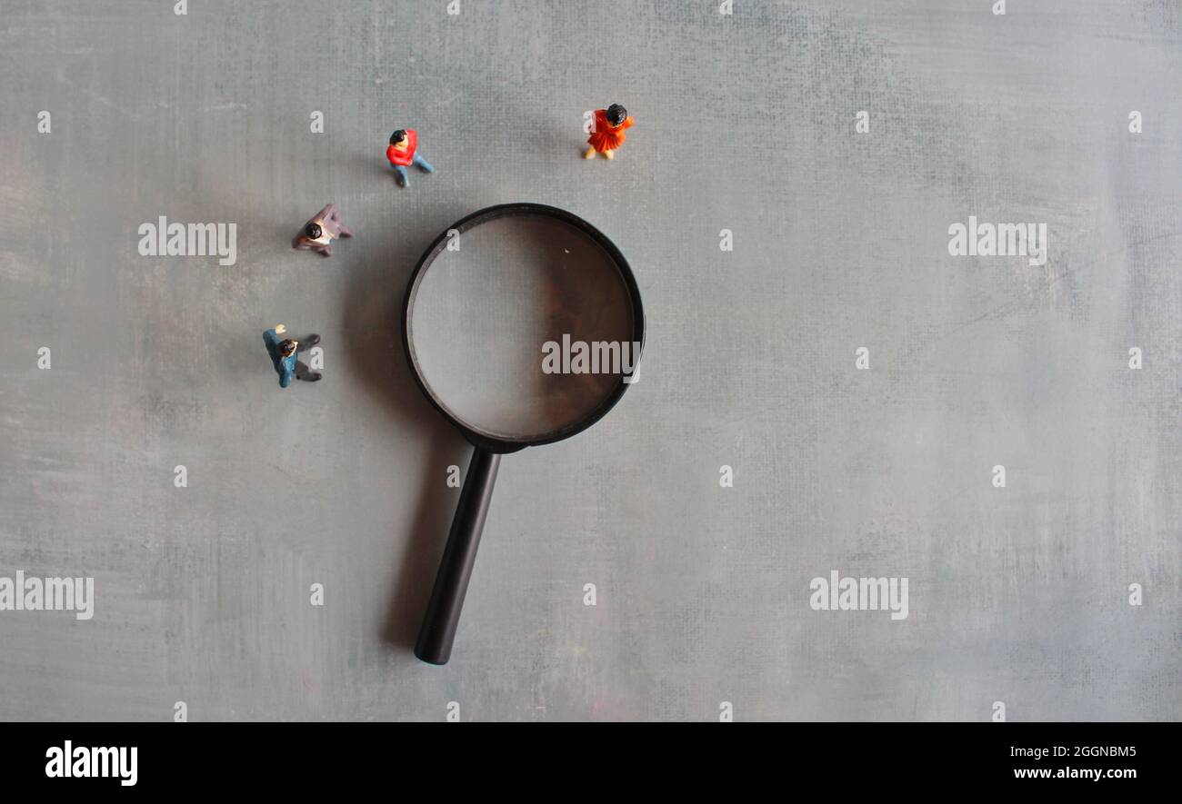 Concept of frequently asked questions, query, investigation, search for information. Miniature people looking at magnifying glass Stock Photo