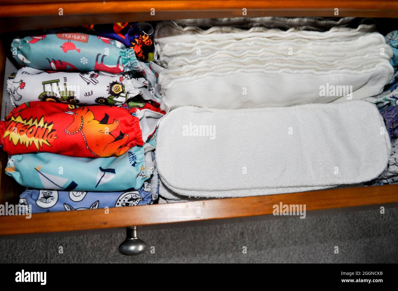 Organised nappy stash in an open drawer. There are nappies (pre stuffed with inserts) and spare bamboo inserts. Stock Photo