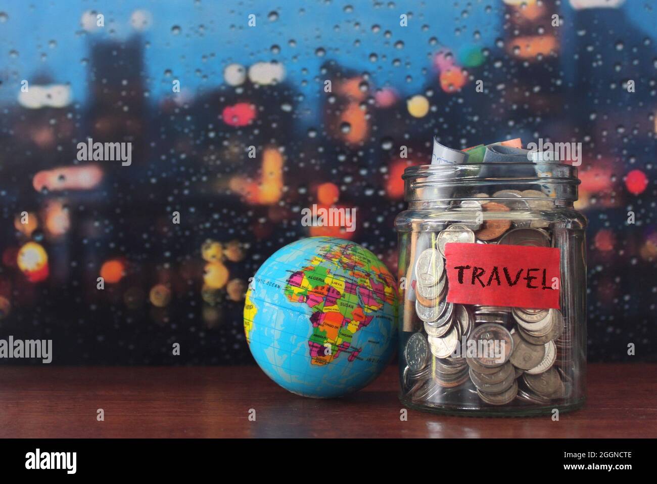 Travel budget concept. Coins in a glass jar and earth globe with copy space for text Stock Photo