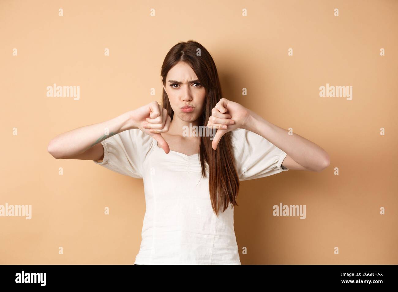Absolutely no. Disappointed young woman frowning and showing thumbs ...