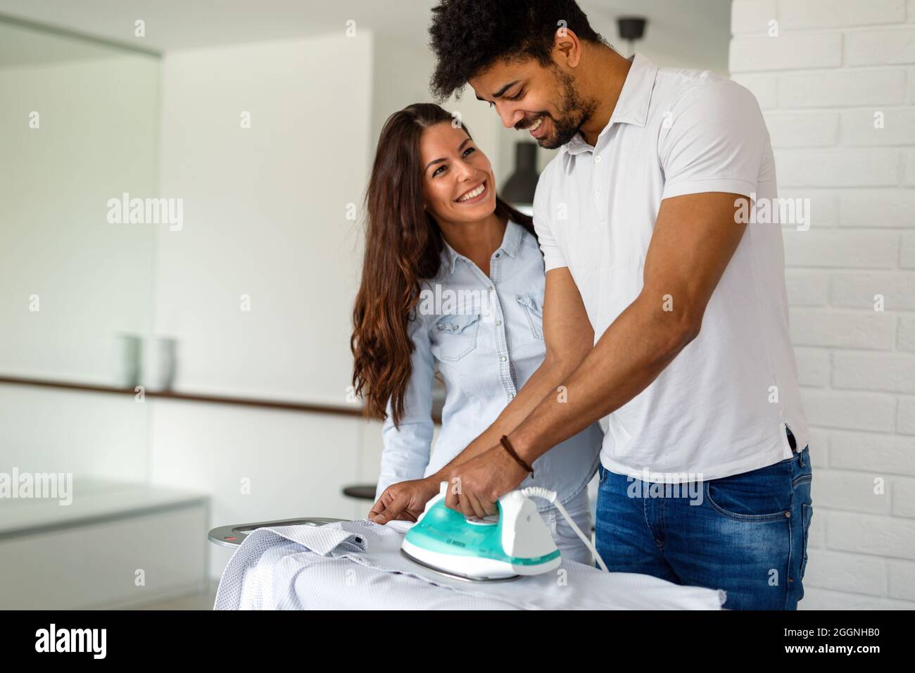 Young couple at home doing hosehold chores and ironing Stock Photo