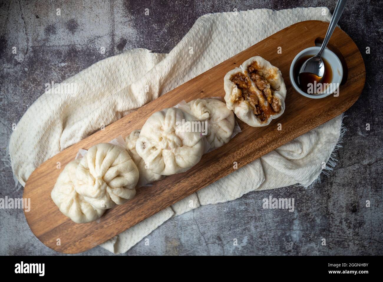 Siopao Asado, Filipino steamed pork bun served on a wooden tray against a concrete background Stock Photo