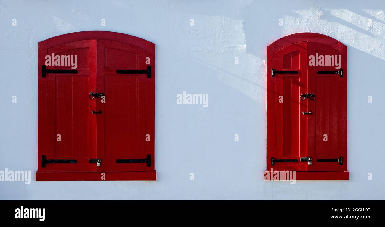 Red painted window shutters on a white painted building Stock Photo