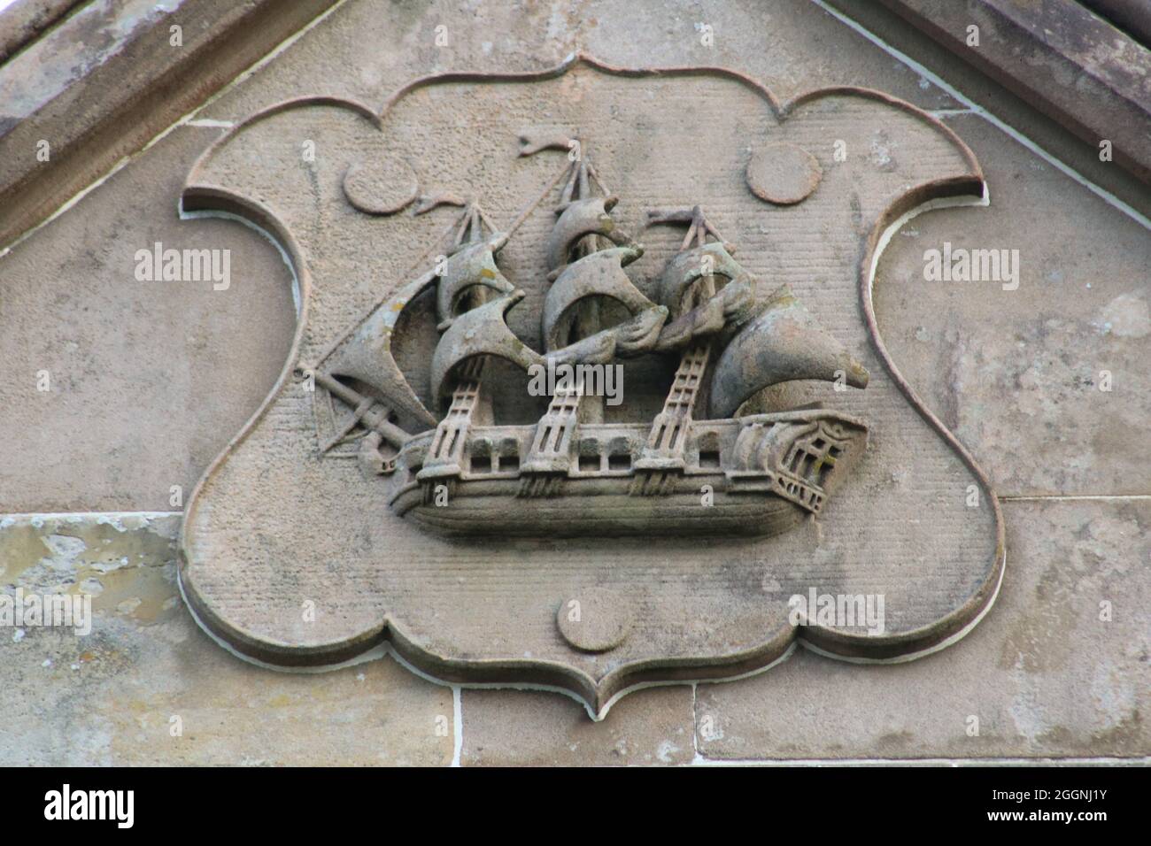 Stone carving of a galleon sailing ship with three masts set in a crest on the wall of a building in Largs Stock Photo