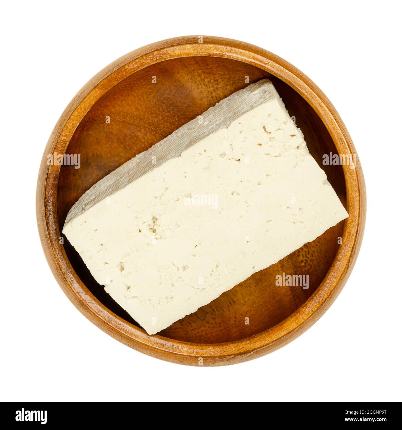 Block of white tofu, in a wooden bowl. Bean curd, coagulated soy milk, pressed into white blocks of different softness. Component of Asian cuisine. Stock Photo