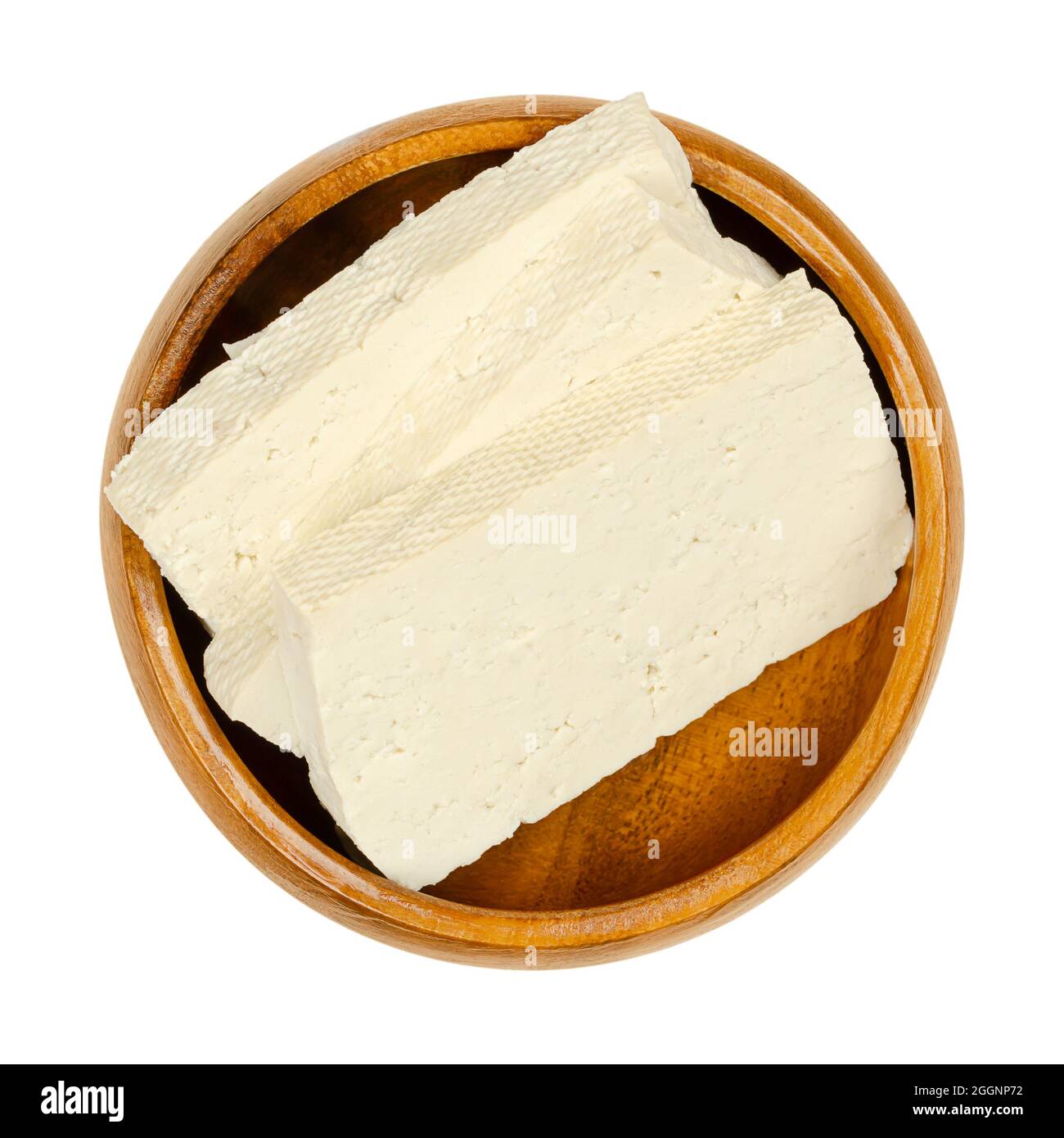Slices of white tofu, in a wooden bowl. Sliced bean curd, coagulated soy milk, pressed into white blocks of different softness. Stock Photo