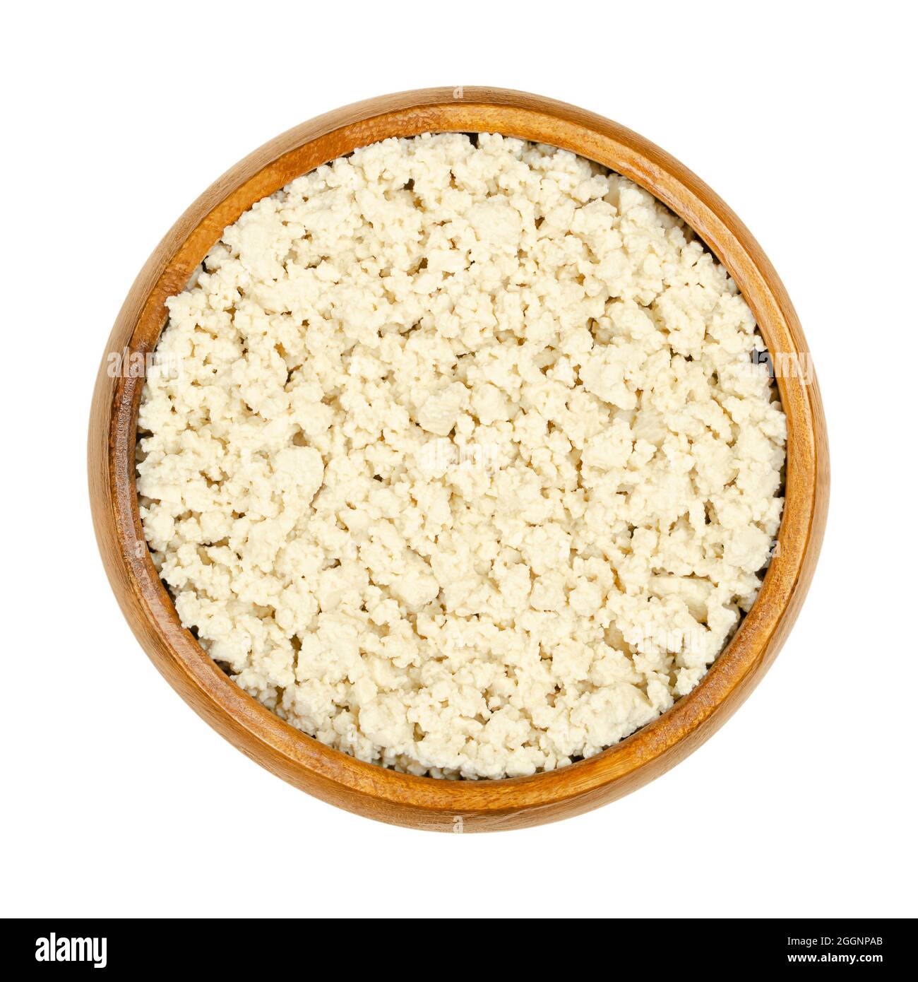 Crumbled white tofu, in a wooden bowl. Mashed bean curd, coagulated soy milk, pressed into white blocks of different softness. Stock Photo