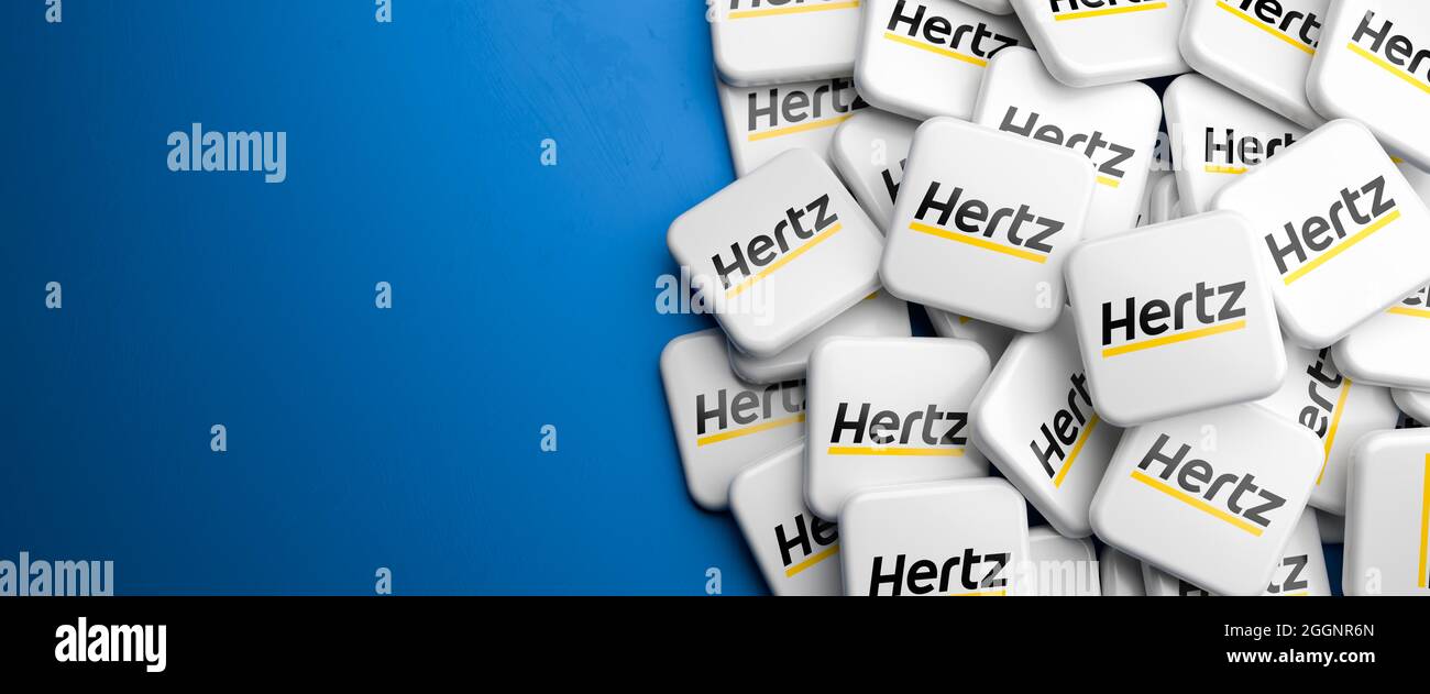 Logos of the rental car company Hertz on a heap on a table. Copy space. Web banner format. Stock Photo
