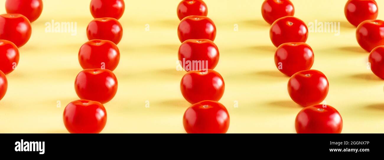 Pattern of red tomatoes on a light yellow background Stock Photo
