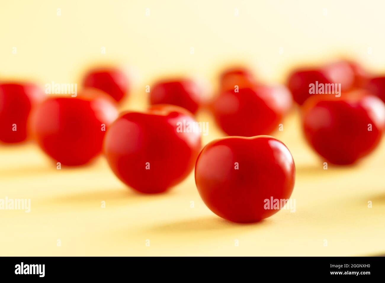 Pattern of red tomatoes on a light yellow background Stock Photo