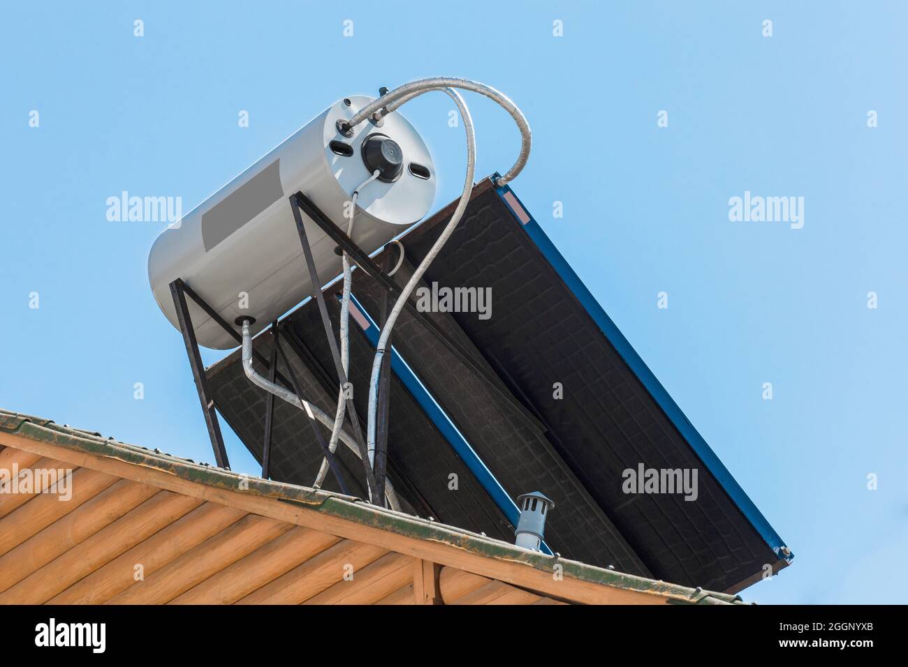 Solar panel energy and modern water heating technologies collector system on the roof of the building against the background of blue sky. Stock Photo