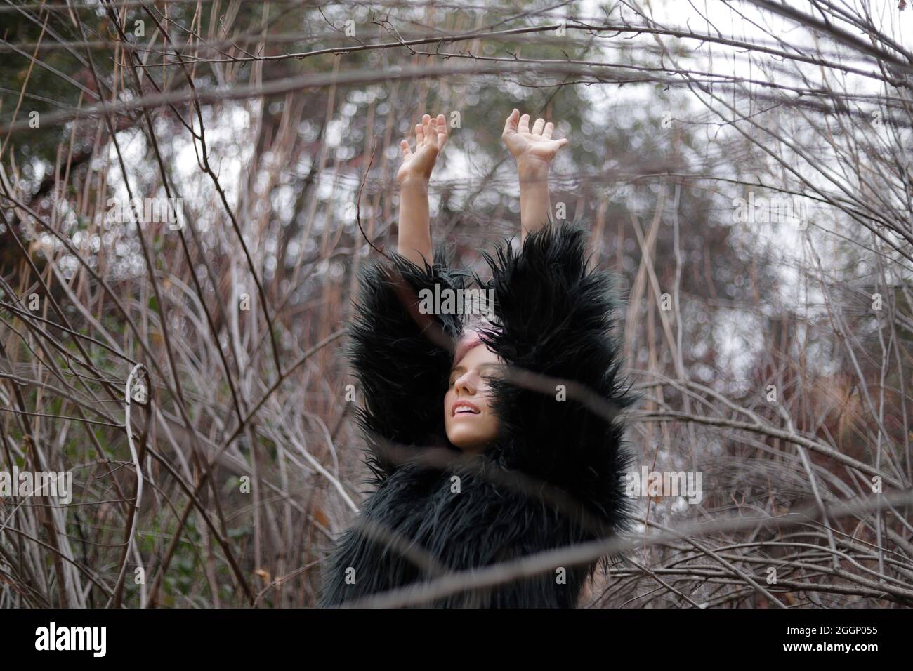 woman in fashionable coat raising her arms and breathing the winter air Stock Photo