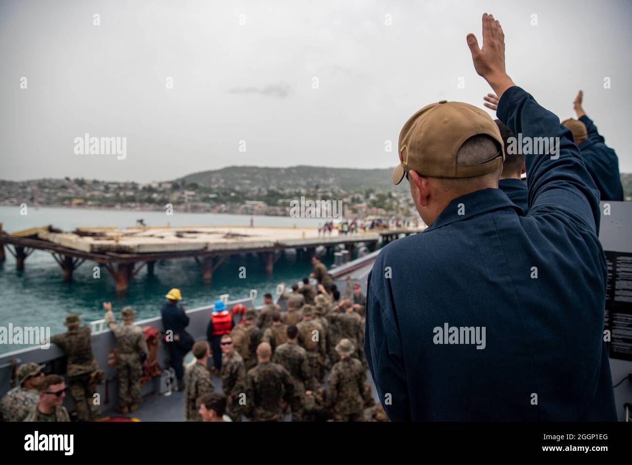 U.S. Sailors and Marines with Joint Task Force-Haiti (JTF-Haiti) wave to locals in Port of Jeremie, Haiti, Aug. 31, 2021. The Marines and sailors aboard the USS Arlington (LPD 24) have been working in support of JTF-Haiti for a humanitarian assistance and disaster relief mission. (U.S. Marine Corps photo by Cpl. Alize Sotelo) Stock Photo