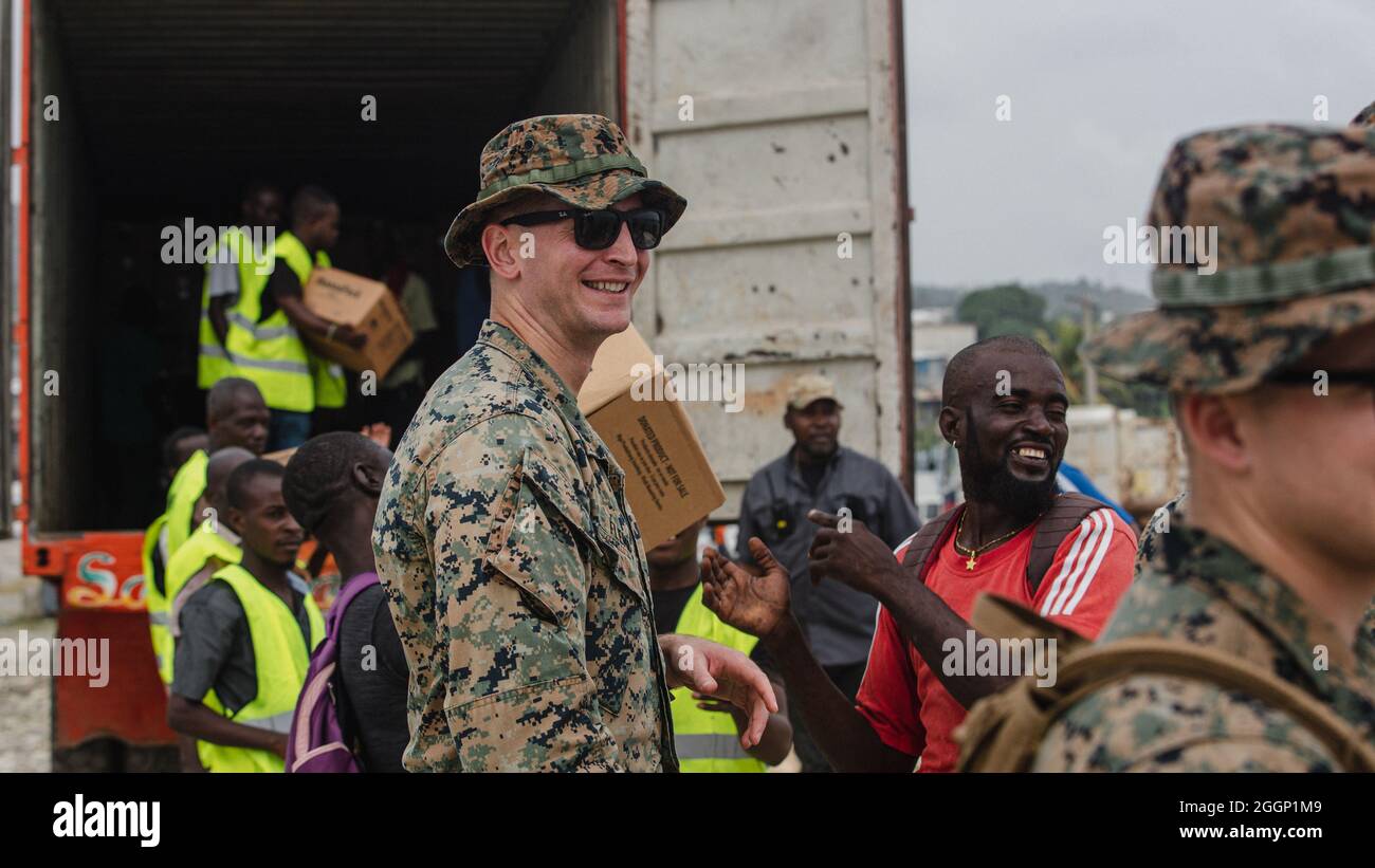 U.S. Marine Corps Capt. Steven Fleming, a native of Egg Harbor Township, N.J., and a forward air controller with 1st Battalion, 6th Marine Regiment, 2d Marine Division, helps offload boxes for redistribution with local volunteers in Port of Jeremie, Haiti, Aug. 31, 2021.  “It is very rewarding to be here and offer support to those in need,” Fleming said. The Marines and sailors aboard the USS Arlington (LPD 24) have been serving in support of Joint Task Force-Haiti for a humanitarian assistance and disaster relief mission. “I am so proud of the commitment our Marines demonstrated today. Nearly Stock Photo