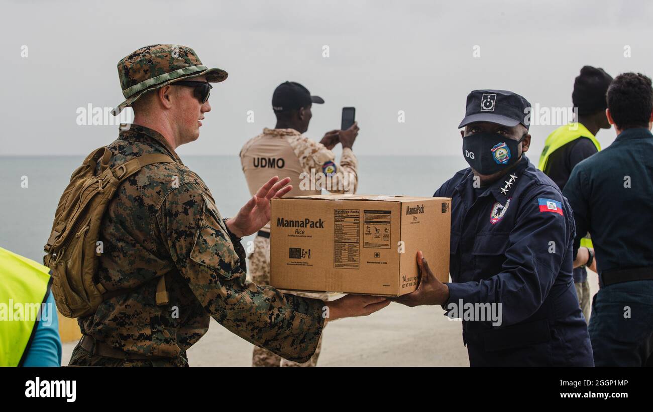 A U.S. Marine with Joint Task Force-Haiti (JTF-Haiti) and a Haitian Police Chief help offload boxes for redistribution in Port of Jeremie, Haiti, Aug. 31, 2021. The Marines and sailors aboard the USS Arlington (LPD 24) have been working in support of JTF-Haiti for a humanitarian assistance and disaster relief mission. (U.S. Marine Corps photo by Lance Cpl. Jacqueline C. Arre) Stock Photo