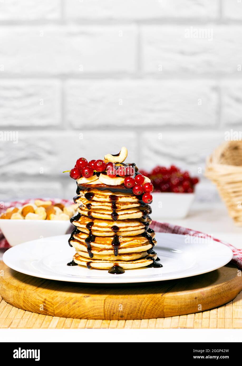 Pancakes With banana, nuts and red currant on white background, Traditional American Breakfast, Copyspace, Vertical Resolution Stock Photo