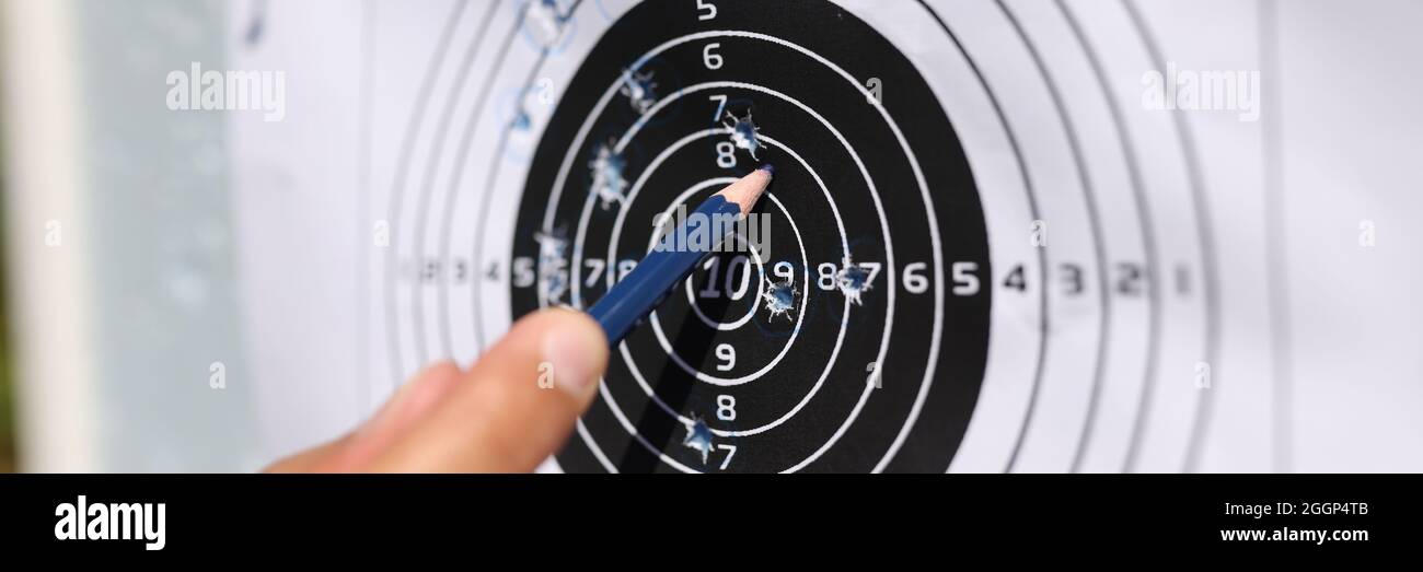 Man showing with pencil to shots on paper target closeup Stock Photo