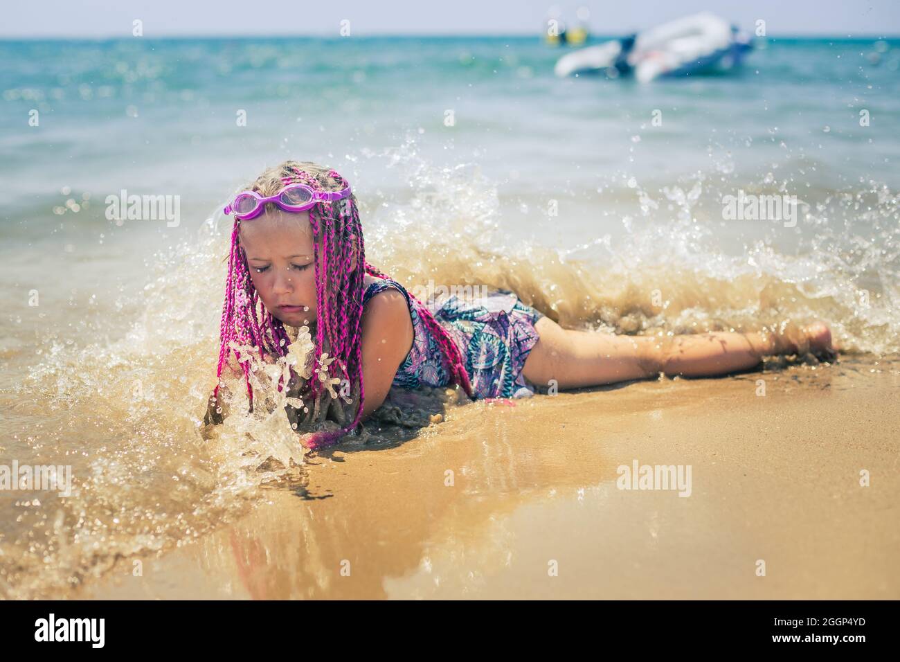 A girl with pink pigtails lies on the beach Stock Photo