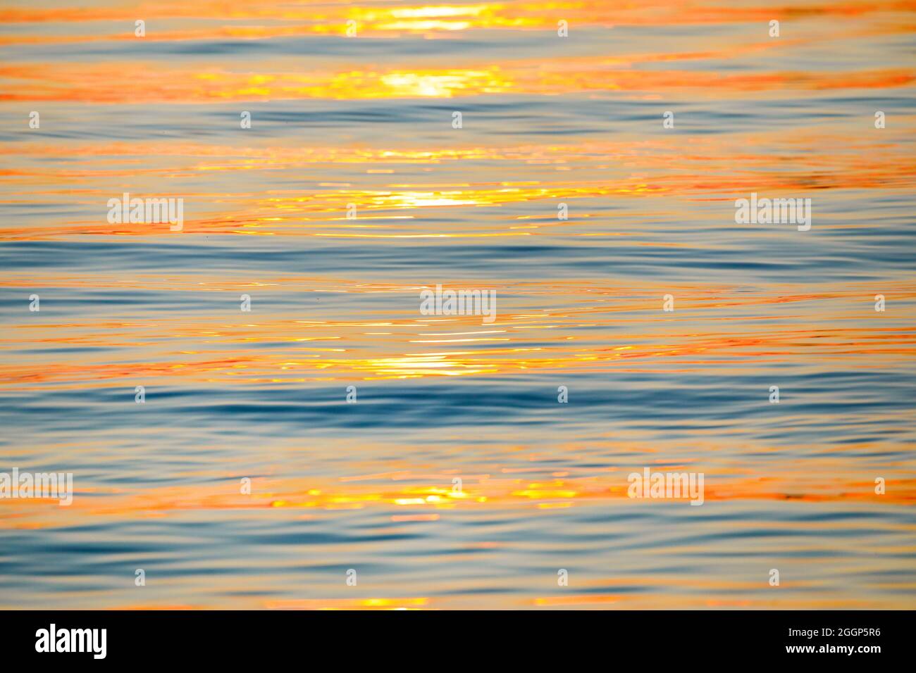 Sonnenstrahlen reflektieren auf Wasseroberfläche vom Bodensee bei Sonnenaufgang und bilden ein abstraktes Muster Stock Photo